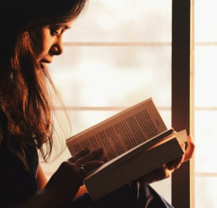 Kobieta czyta książkę Fantazy siedząc przy oknie